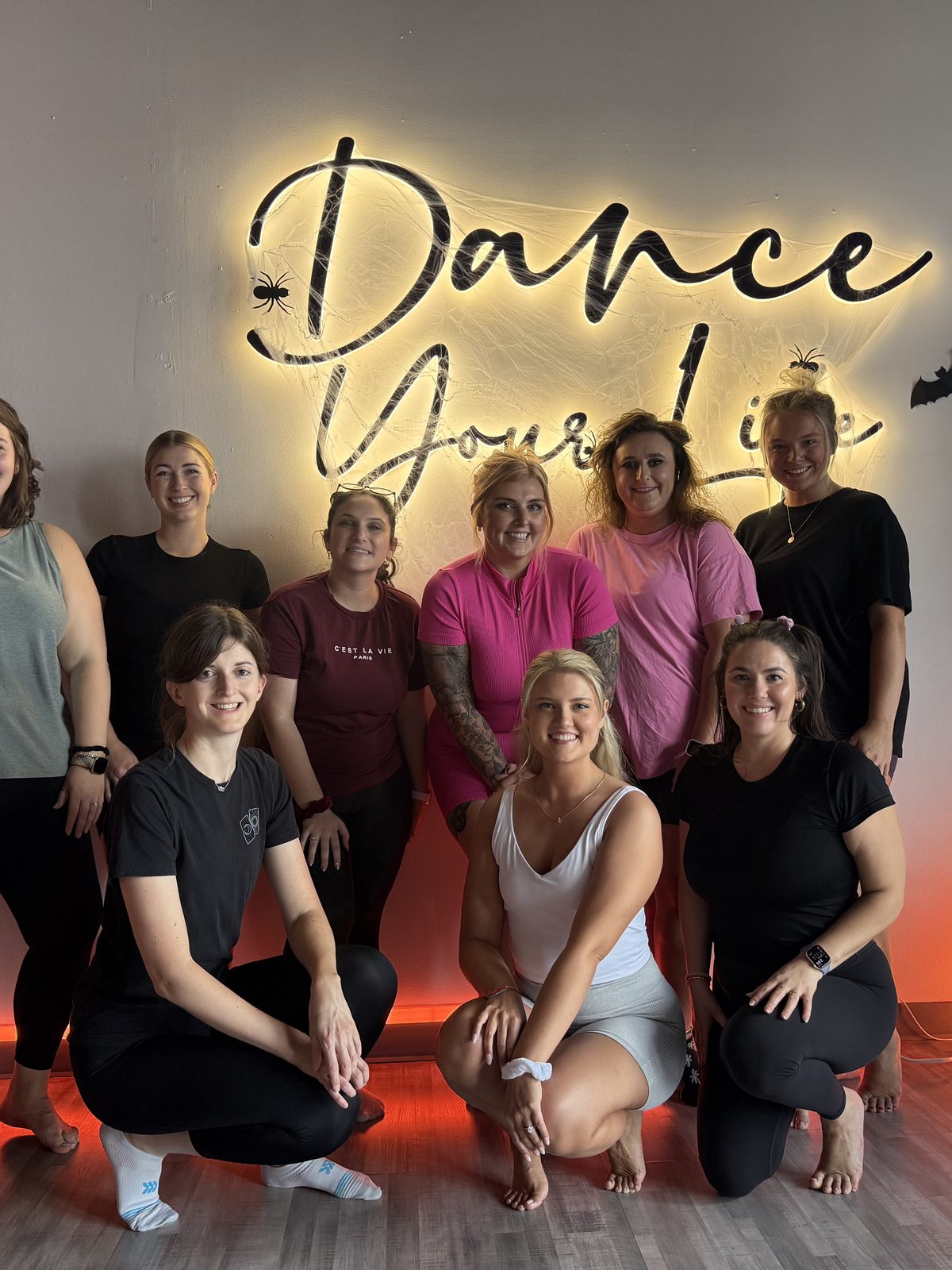 Bachelorette party posing in front of the Dance Your Life neon sign at the Charleston studio